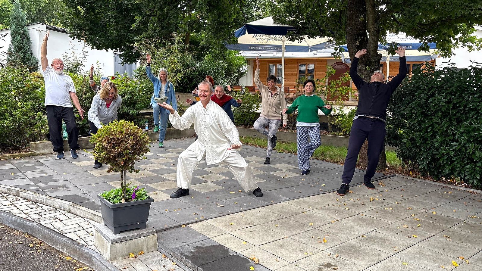 Gruppe übt Tai Chi auf einer Terrasse im Freien